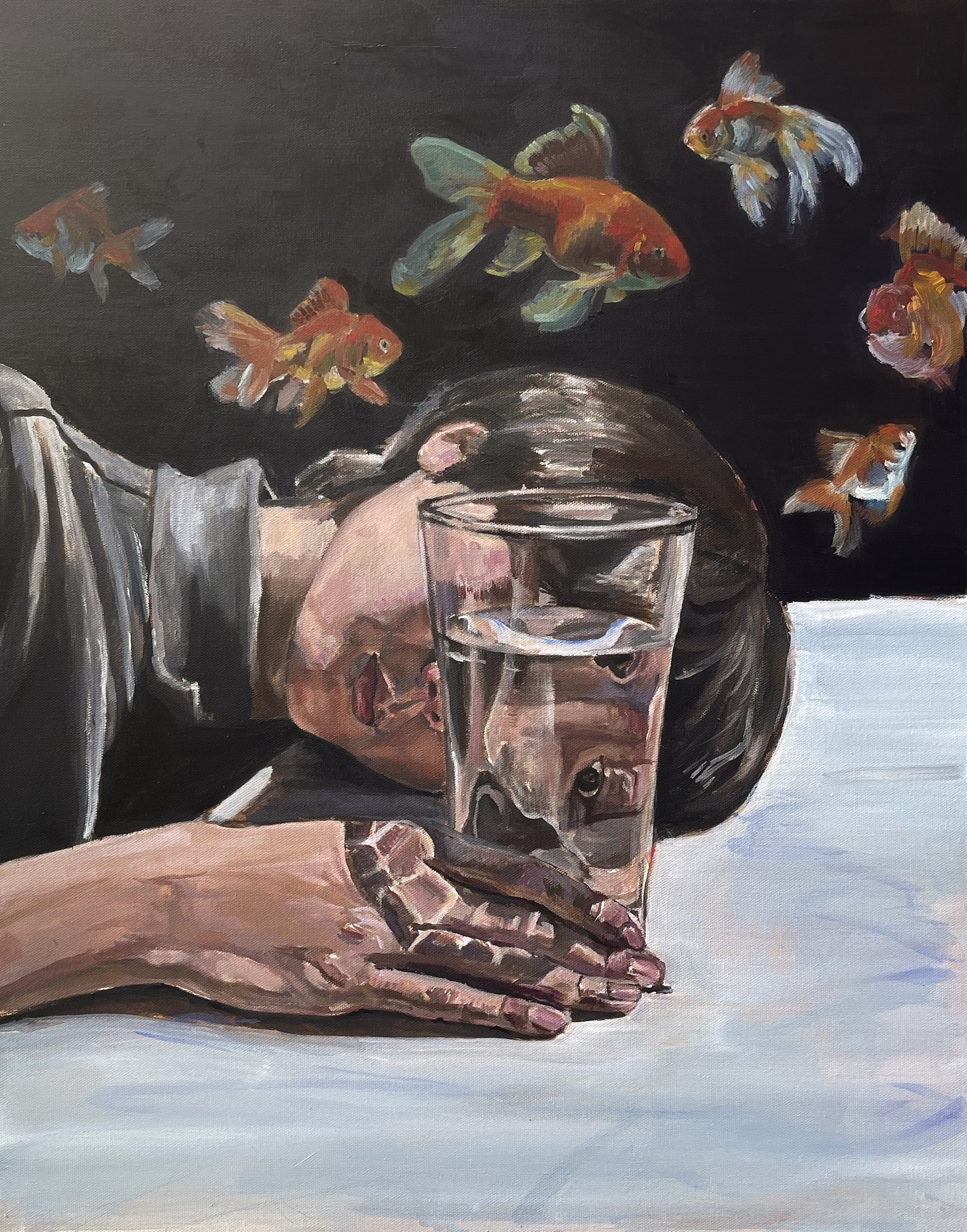 person looking into glass of water with goldfish in background